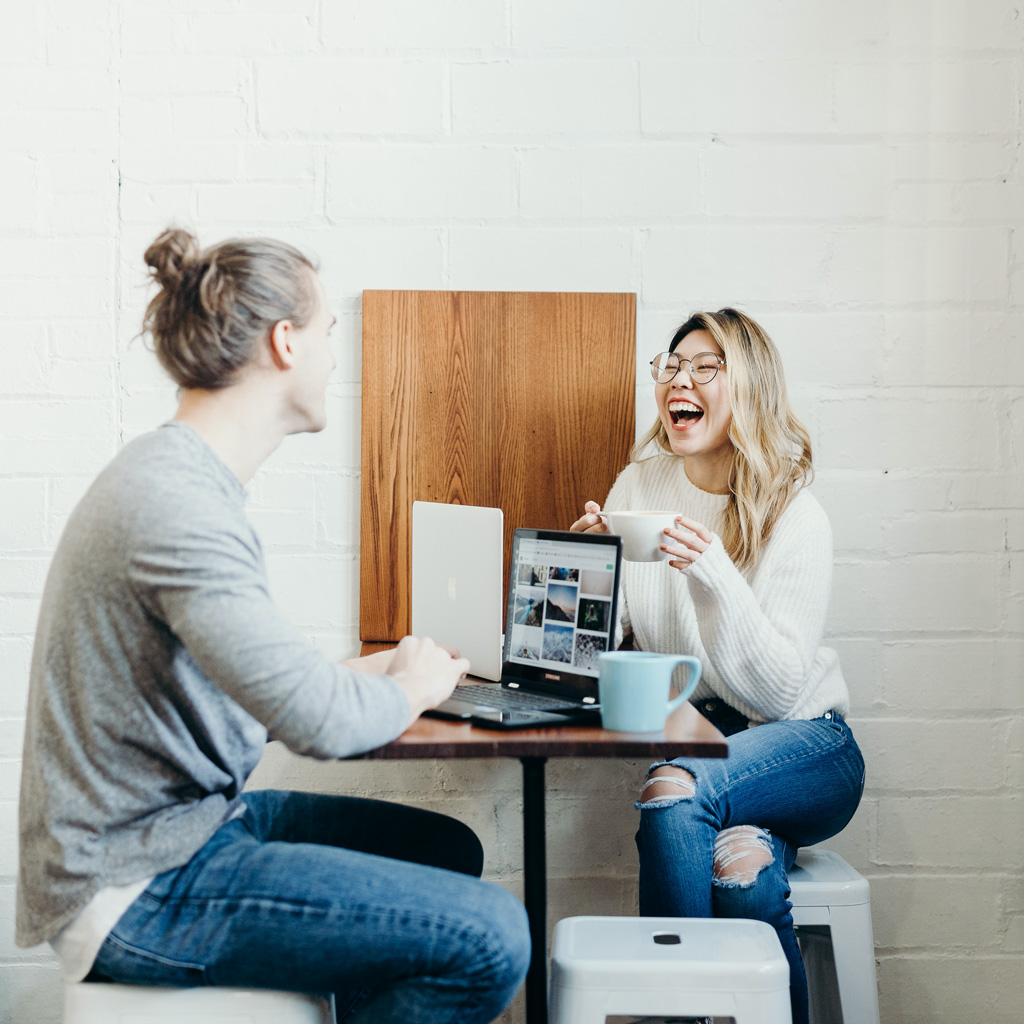 Deux personnes configurant un site web tout en discutant autour d'une tasse de café